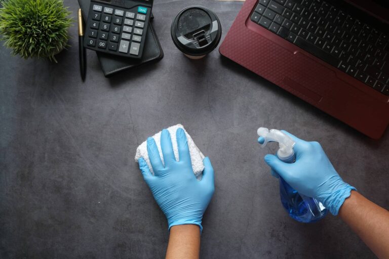 Professional cleaner cleaning surface near laptop